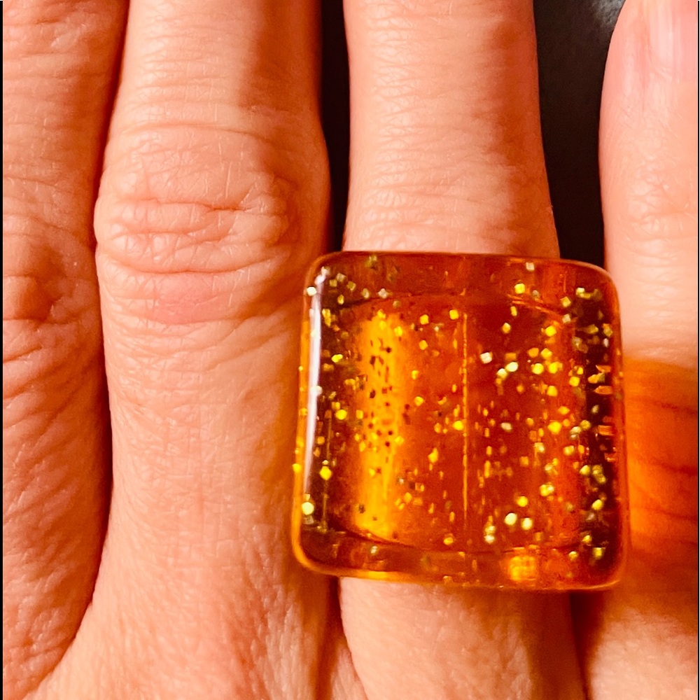 Lucite amber color w/ sparkles ring. Size 5 & 3/4